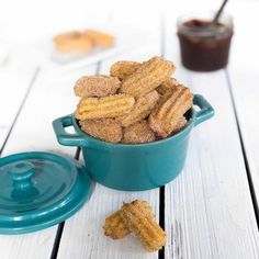 a blue pot filled with fried food sitting on top of a white wooden table next to a jar