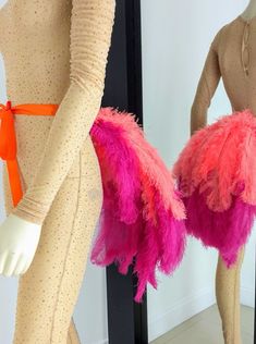 two mannequins with pink and orange feathers on them