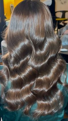 the back of a woman's head with long, wavy hair in a salon