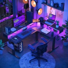 a desk with two laptops on it in front of a purple light and some plants