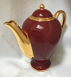 a red tea pot with gold trimmings on it