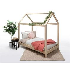 a bed with a canopy and pillows on top of it next to a potted plant