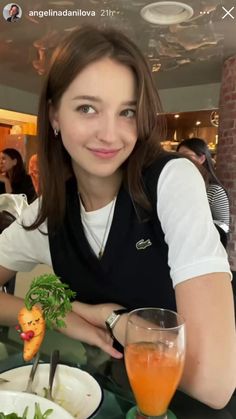 a woman sitting at a table with a glass of orange juice in front of her