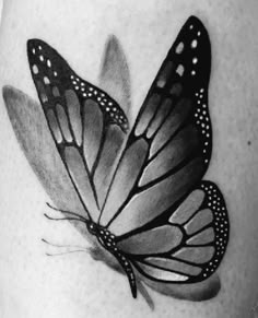 a black and white photo of a butterfly on the side of a woman's thigh