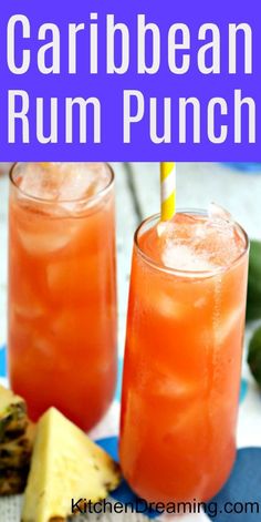 two glasses filled with orange rum punch on top of a blue and white plate next to sliced pineapple