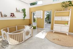 a baby's room with yellow walls and white furniture