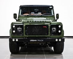 the front end of a green land rover in a white room with tile flooring