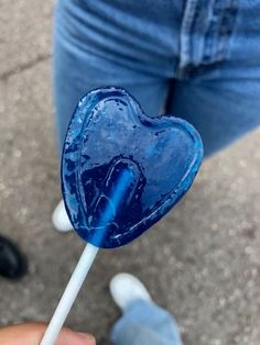 a blue lollipop in the shape of a heart being held by someone's hand