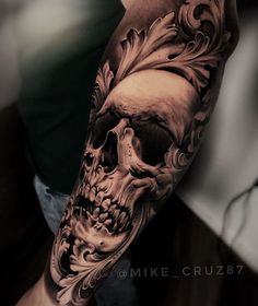 a man's arm with a skull and flowers tattoo design on the left forearm