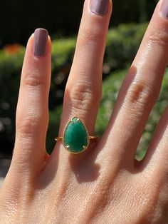 a woman's hand with a ring on it and a green stone in the middle