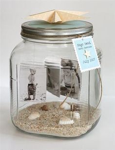 a glass jar filled with sand and shells next to a small card on top of it