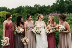 a group of women standing next to each other wearing dresses and holding bouquets in their hands