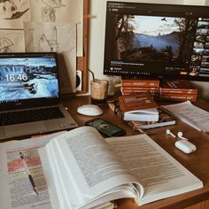 an open book sitting on top of a desk next to a laptop computer and monitor