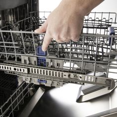 a hand reaching into the dishwasher for something to put in it's compartment