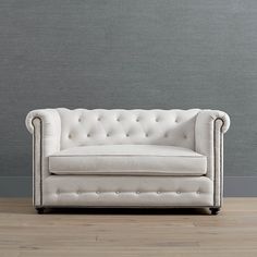 a white couch sitting on top of a hard wood floor next to a gray wall