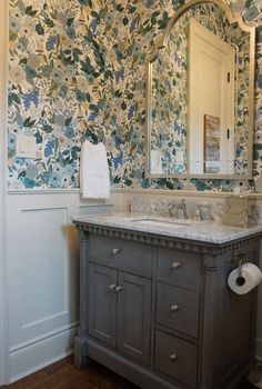 a bathroom with floral wallpaper and marble counter top