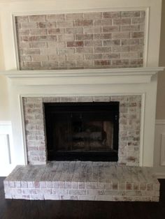 a brick fireplace in a living room with hardwood flooring and white painted bricks on the mantle