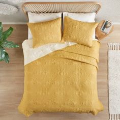 an overhead view of a bed with yellow linens and pillows, along with a potted plant