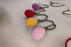 crocheted ornaments are arranged on a white tablecloth with red, yellow, and green string