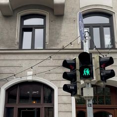 a traffic light sitting in front of a tall building with lots of windows on it