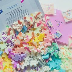 a pile of colorful pieces of puzzle on top of a table next to an open book