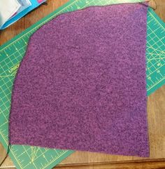 three pieces of purple fabric sitting on top of a cutting board next to a pair of scissors