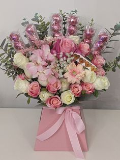 a bouquet of pink and white flowers with chocolates in the middle on a table