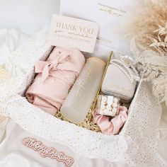 an open gift box filled with personal care items on top of a white bed sheet