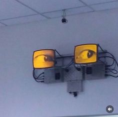 two yellow lights are on the wall with wires attached to them and one is upside down