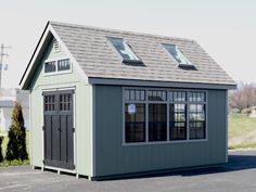 a small green shed with windows and a gray roof