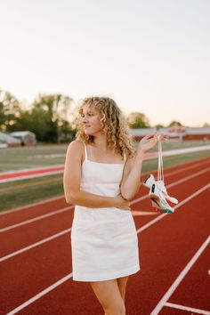 a woman in a white dress is standing on a track