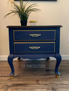 a blue dresser with gold trimming and a potted plant on top