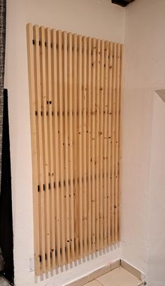 a white toilet sitting next to a wooden radiator in a room with wood slats on the wall