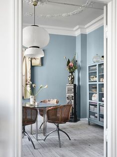 two chairs and a table in a room with light blue walls, white trim and wood flooring