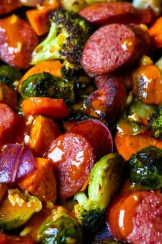 a close up view of cooked vegetables including broccoli, carrots and sausage