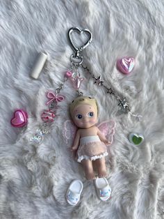 a keychain with a little angel doll and other items laying on a fur surface