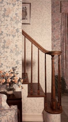 a vase with flowers sitting on top of a wooden bannister next to a stair case