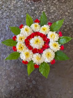 a vase filled with white and red flowers on top of a table covered in pebbles