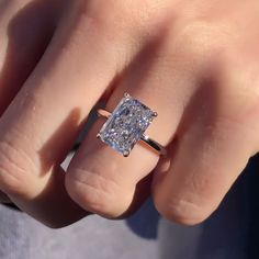 a close up of a person's hand holding a ring with a diamond in it