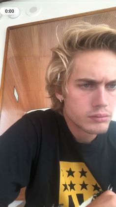 a young man with blonde hair is looking at the camera