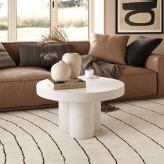 a living room with a brown couch and white coffee table in front of large windows