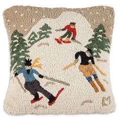 an embroidered pillow with skiers skiing on the snow covered ground and trees in the background