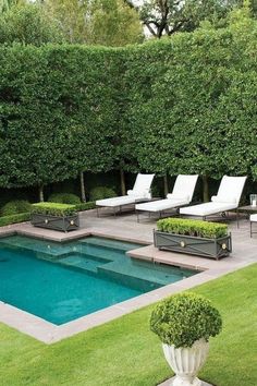 an outdoor swimming pool with lounge chairs and trees in the back ground, surrounded by grass