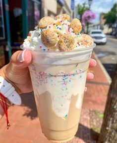 a person holding up a cup with ice cream and sprinkles on it