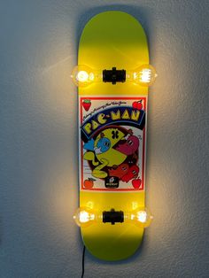 a yellow skateboard mounted to the side of a wall with two lights on it