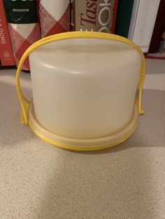 a white and yellow container sitting on top of a counter next to bookshelves