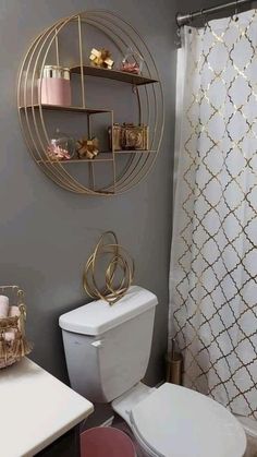 a white toilet sitting next to a bath tub in a bathroom under a gold circular shelf