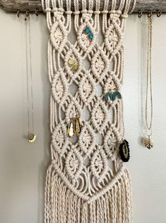 a macrame wall hanging with beads and other jewelry on it's side