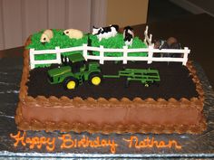 a birthday cake with farm animals and tractor on the top is decorated in chocolate icing