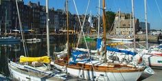 several sailboats are docked in the water at a marina with buildings on either side